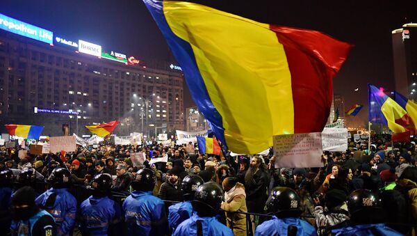 Romanian riot police stand guard as people demonstrate against controversial decrees to pardon corrupt politicians and decriminalize other offenses in front of the government headquarters in Bucharest, on February 1, 2017 - Sputnik International