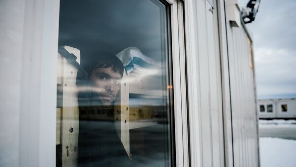 A refugee looks through a window in the sleeping facilities at the arrival centre for refugees near the town on Kirkenes in northern Norway close to the border with Russia on November 11, 2015 - Sputnik International
