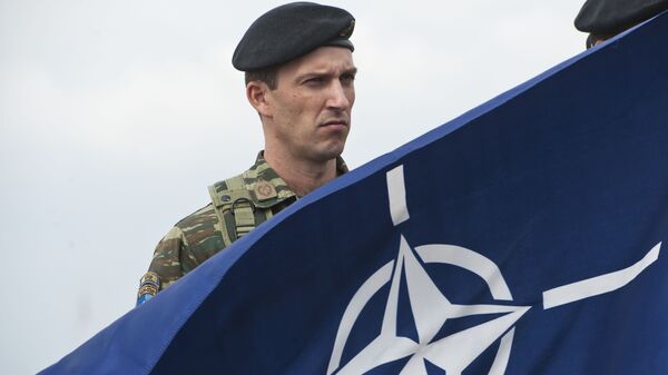 A members of NATO-led peacekeepers in Kosovo (KFOR) holds the NATO flag during the change of command ceremony in Pristina on September 3, 2014. - Sputnik International
