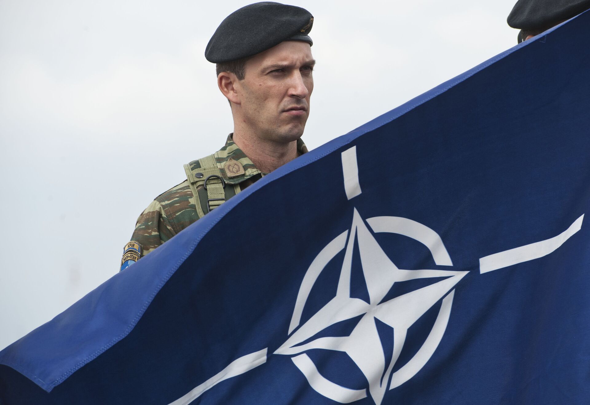 A members of NATO-led peacekeepers in Kosovo (KFOR) holds the NATO flag during the change of command ceremony in Pristina on September 3, 2014.  - Sputnik International, 1920, 22.11.2022