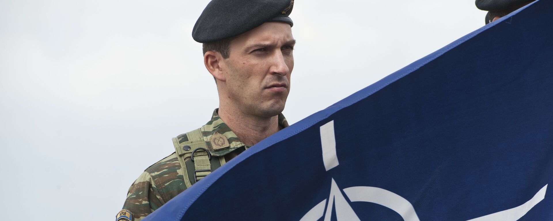 A members of NATO-led peacekeepers in Kosovo (KFOR) holds the NATO flag during the change of command ceremony in Pristina on September 3, 2014.  - Sputnik International, 1920, 01.01.2023