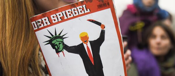 A young woman holds the last edition of Der Spiegel magazine with a cover designed by Edel Rodriguez, as she protests against the travel ban imposed by US President Donald Trump, on February 4, 2017, in Berlin A young woman holds the last edition of Der Spiegel magazine with a cover designed by Edel Rodriguez, as she protests against the travel ban imposed by US President Donald Trump, on February 4, 2017, in Berlin - Sputnik International