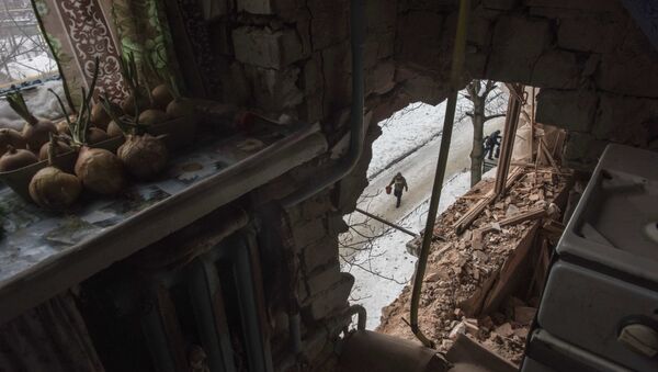 A local resident walking in a street is seen through a hole in an apartment building damaged by shelling in Avdiivka, Ukraine, Saturday, Feb. 4, 2017 - Sputnik International