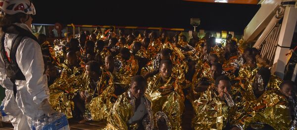 Migrants and refugees wrapped in survival foil blankets rest during a rescue operation by the Topaz Responder ship, run by Maltese NGO Moas and the Italian Red Cross, on November 4, 2016 Migrants and refugees wrapped in survival foil blankets rest during a rescue operation by the Topaz Responder ship, run by Maltese NGO Moas and the Italian Red Cross, on November 4, 2016 - Sputnik International