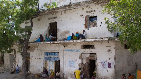 People rest along a bullet-ridden building in Mogadishu, Somalia - Sputnik International