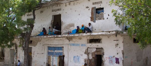 People rest along a bullet-ridden building in Mogadishu, Somalia - Sputnik International