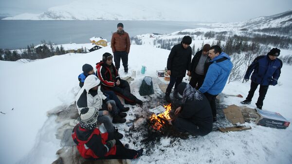 Asylum seekers gather round a fire as they cook a meal overlooking the temporary Altnes camp refugee camp on the island of Seiland, northern Norway - Sputnik International