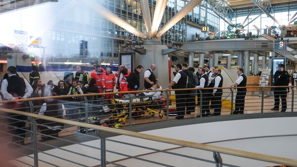 Firefighters take care of a person on a stretcher inside Hamburg airport on February 12, 2017 in Hamburg, northern Germany, as German emergency services evacuated the airport after people reported an unusual smell as well as respiratory ailments and watering eyes - Sputnik International
