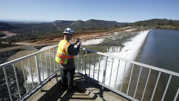 In this Saturday, Feb. 11, 2017, photo, Jason Newton, of the Department of Water Resources, takes a picture of water going over the emergency spillway at Oroville Dam in Oroville, Calif - Sputnik International