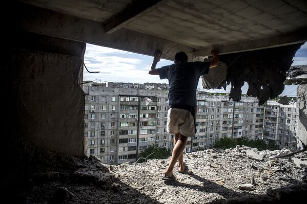 Man inspects damaged residential building in the Mirny district of Lugansk, hit by artillery fire. - Sputnik International