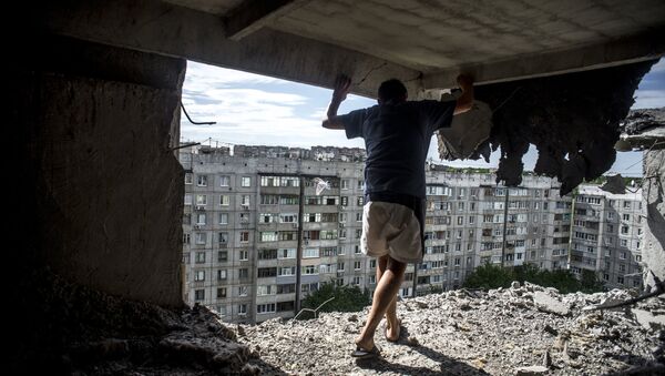 Man inspects damaged residential building in the Mirny district of Lugansk, hit by artillery fire. File photo - Sputnik International