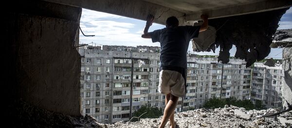 Man inspects damaged residential building in the Mirny district of Lugansk, hit by artillery fire. File photo - Sputnik International