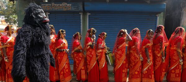 A performer dressed in a chimpanzee costume walks past brides as they arrive at a mass marriage ceremony in which, according to its organizers, 109 tribal, Muslim and Hindu couples from various villages across the state took their wedding vows, at Bahirkhand village, north of Kolkata, India February 5, 2017 A performer dressed in a chimpanzee costume walks past brides as they arrive at a mass marriage ceremony in which, according to its organizers, 109 tribal, Muslim and Hindu couples from various villages across the state took their wedding vows, at Bahirkhand village, north of Kolkata, India February 5, 2017 - Sputnik International