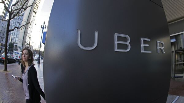 In this file photo taken Tuesday, Dec. 16, 2014, a woman walks past the company logo of the internet car service, Uber, in San Francisco, USA. - Sputnik International