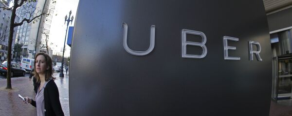 In this file photo taken Tuesday, Dec. 16, 2014, a woman walks past the company logo of the internet car service, Uber, in San Francisco, USA. - Sputnik International