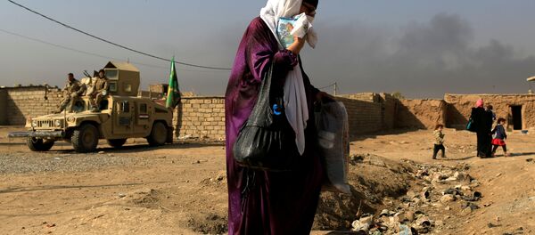 A woman who is fleeing the fighting between Islamic State and the Iraqi army in the Intisar district of eastern Mosul, walks past a military humvee while heading to safer territory in Iraq November 7, 2016. A woman who is fleeing the fighting between Islamic State and the Iraqi army in the Intisar district of eastern Mosul, walks past a military humvee while heading to safer territory in Iraq November 7, 2016. - Sputnik International