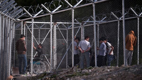 Migrants stand behind a fence at the VIAL detention center on the island of Chios where migrants and refugees arrived after the March 20 EU-Turkey deal are kept, on April 4, 2016 - Sputnik International