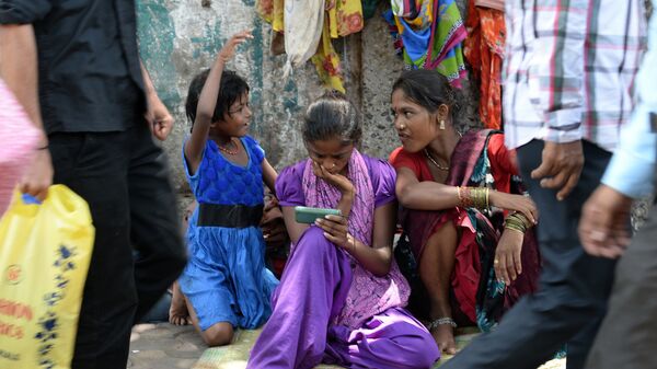 An Indian pavement dweller watches a movie on a mobile phone as others interact in Mumbai on June 3, 2015 - Sputnik International