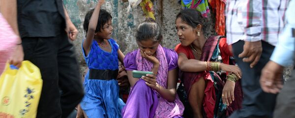 An Indian pavement dweller watches a movie on a mobile phone as others interact in Mumbai on June 3, 2015 - Sputnik International