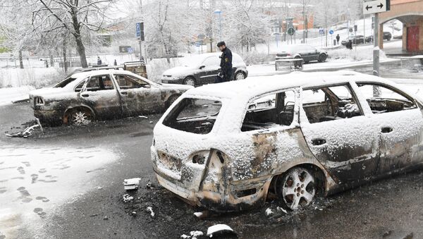 A policeman investigates a burnt car in the Rinkeby suburb outside Stockholm, Sweden February 21, 2017 - Sputnik International