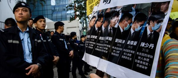 Police (L) stand guard as pro-democracy supporters (R) chant slogans and hold placards after the arrival of the seven police officers (pictured in placard on right), who were found guilty on February 14 of assaulting activist Ken Tsang during the 2014 pro-democracy protests, outside the District Court in Hong Kong on February 17, 2017 Police (L) stand guard as pro-democracy supporters (R) chant slogans and hold placards after the arrival of the seven police officers (pictured in placard on right), who were found guilty on February 14 of assaulting activist Ken Tsang during the 2014 pro-democracy protests, outside the District Court in Hong Kong on February 17, 2017 - Sputnik International