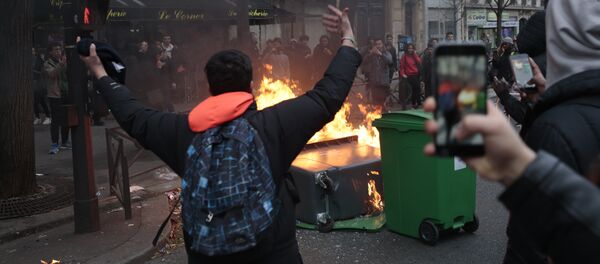 A young man gestures in front of burning dustbins which obstruct the street, during a protest of students against police brutality, following the alleged rape of Theo, next to the Lycee Voltaire secondary school in Paris, on February 23, 2017 A young man gestures in front of burning dustbins which obstruct the street, during a protest of students against police brutality, following the alleged rape of Theo, next to the Lycee Voltaire secondary school in Paris, on February 23, 2017 - Sputnik International