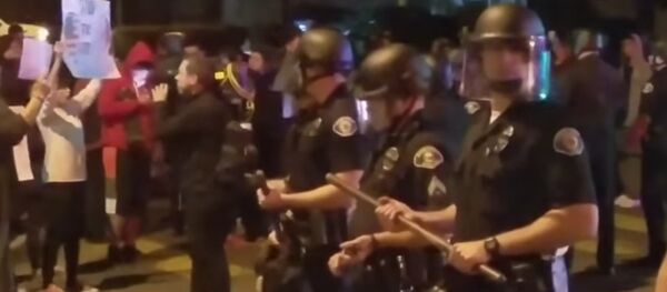 Police stand guard as demonstrators protests an off-duty LAPD officers firing his weapon at an unarmed teenage boy. - Sputnik International