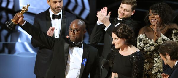 89th Academy Awards - Oscars Awards Show - Hollywood, California, U.S. - 26/02/17 - Writer and Director Barry Jenkins of Moonlight holds up the Best Picture Oscar in front of host Jimmy Kimmel (rear) as he stands with Producer Adele Romanski (R). 89th Academy Awards - Oscars Awards Show - Hollywood, California, U.S. - 26/02/17 - Writer and Director Barry Jenkins of Moonlight holds up the Best Picture Oscar in front of host Jimmy Kimmel (rear) as he stands with Producer Adele Romanski (R). - Sputnik International