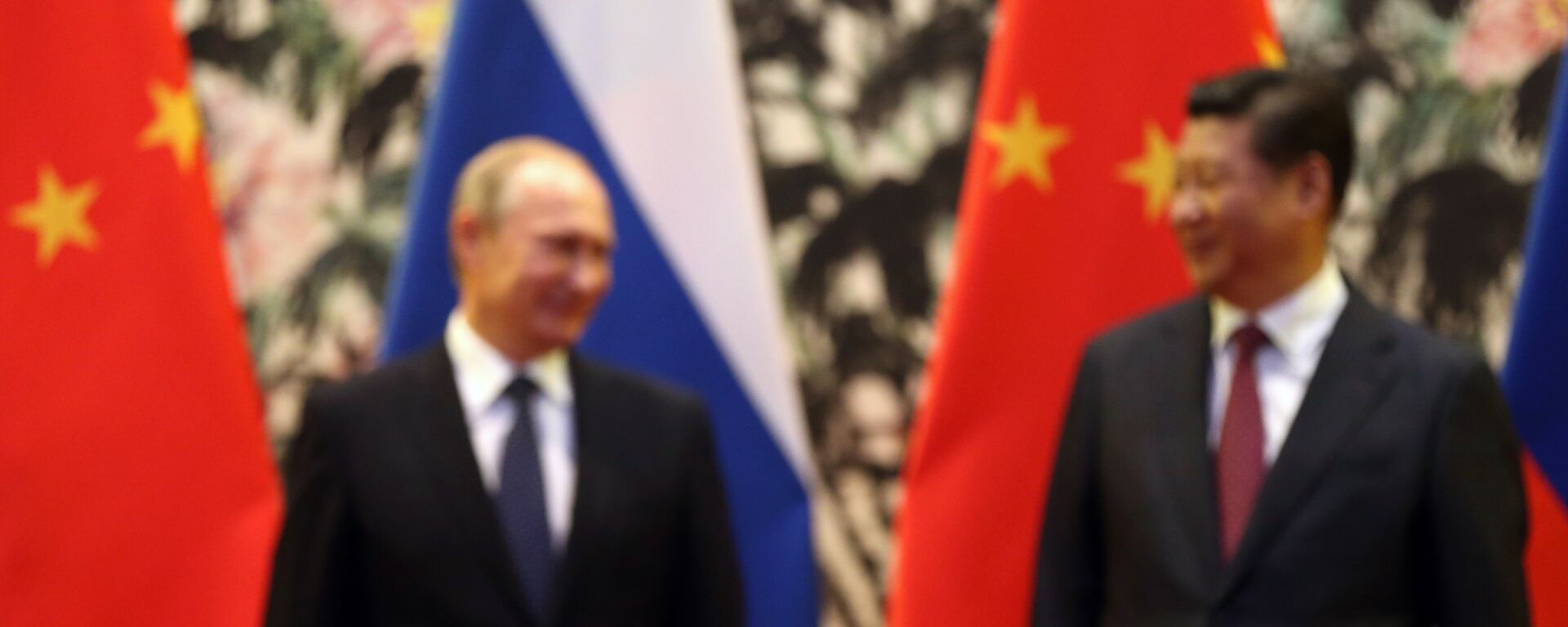 The Russian and Chinese national flags are seen on the table as Russia's President Vladimir Putin (back L) and his China's President Xi Jinping (back R) stand during a signing ceremony at the Diaoyutai State Guesthouse in Beijing on November 9, 2014. - Sputnik International, 1920, 17.07.2022