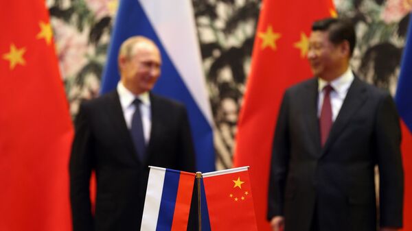 The Russian and Chinese national flags are seen on the table as Russia's President Vladimir Putin (back L) and his China's President Xi Jinping (back R) stand during a signing ceremony at the Diaoyutai State Guesthouse in Beijing on November 9, 2014. - Sputnik International