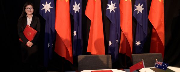 A woman holding a copy of the free trade agreement (FTA) stands next to national flags of China and Australia (File) A woman holding a copy of the free trade agreement (FTA) stands next to national flags of China and Australia (File) - Sputnik International