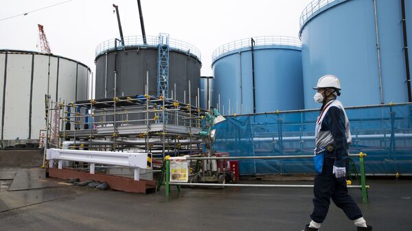 A Tokyo Electric Power Co.'s (TEPCO) employee walks past storage tanks for contaminated water at the company's Fukushima Dai-ichi nuclear power plant in Okuma, Fukushima, Japan, on February 23, 2017 - Sputnik International