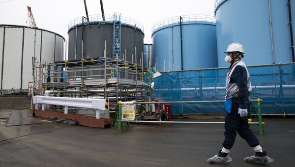 A Tokyo Electric Power Co.'s (TEPCO) employee walks past storage tanks for contaminated water at the company's Fukushima Dai-ichi nuclear power plant in Okuma, Fukushima, Japan, on February 23, 2017 - Sputnik International