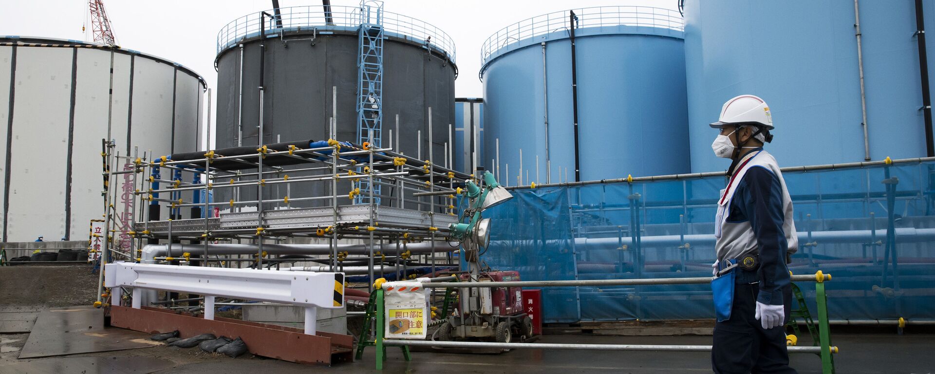 A Tokyo Electric Power Co.'s (TEPCO) employee walks past storage tanks for contaminated water at the company's Fukushima Dai-ichi nuclear power plant in Okuma, Fukushima, Japan, on February 23, 2017 - Sputnik International, 1920, 12.04.2024