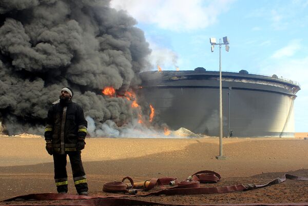 A Libyan fireman stands in front of smoke and flames rising from an oil storage tank at an oil facility in northern Libya's Ras Lanouf region on January 23, 2016, after it was set ablaze earlier in the week following attacks launched by Islamic State (IS) group jihadists to seize key port terminals. A Libyan fireman stands in front of smoke and flames rising from an oil storage tank at an oil facility in northern Libya's Ras Lanouf region on January 23, 2016, after it was set ablaze earlier in the week following attacks launched by Islamic State (IS) group jihadists to seize key port terminals. - Sputnik International
