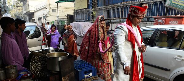 Newly married Indian man Rohit Aggarwal (R) is watched by relatives and street vendors as he leads his wife Shally Aggarwal (2R) to their home after visiting a temple in New Delhi on February 16, 2017 Newly married Indian man Rohit Aggarwal (R) is watched by relatives and street vendors as he leads his wife Shally Aggarwal (2R) to their home after visiting a temple in New Delhi on February 16, 2017 - Sputnik International