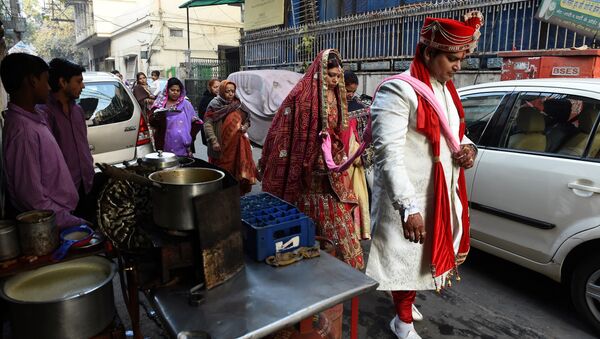 Newly married Indian man Rohit Aggarwal (R) is watched by relatives and street vendors as he leads his wife Shally Aggarwal (2R) to their home after visiting a temple in New Delhi on February 16, 2017 - Sputnik International