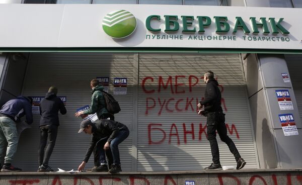 Radicals in front of a Sberbank branch in Kiev, putting up posters which read Attention! This is a bank of an aggressor country. It will be closed. Urgently withdraw your money!, during a protest. Graffiti reads Death to Russian banks. March 10, 2017 - Sputnik International