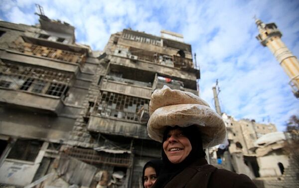 Syrian woman carries bags of bread on her head at the one of the street in Aleppo - Sputnik International