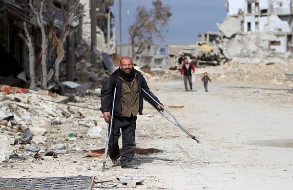 Syrian man walking past damaged buildings in Aleppo  - Sputnik International