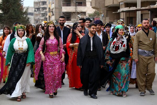 A group of Syrian-Kurdish men and women dressed in traditional Kurdish attire walk down the street in the northeastern Syrian city of Qamishli celebrating the Day of Kurdish Clothing. - Sputnik International