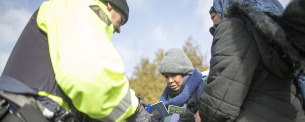 An RCMP officer checks the documents of two women from Sudan after they illegally crossed the Canada-US border. (File) - Sputnik International