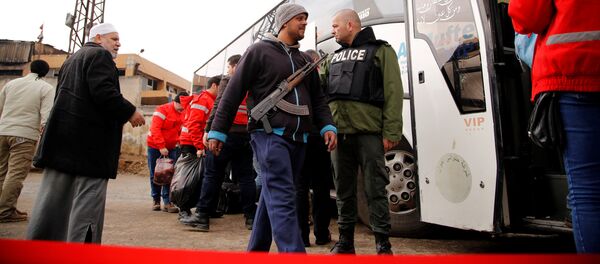 A rebel fighter walks with his weapon past a Syrian security personnel towards a bus to evacuate the besieged Waer district in the central Syrian city of Homs, after an agreement reached between rebels and Syria's army, Syria March 18, 2017 A rebel fighter walks with his weapon past a Syrian security personnel towards a bus to evacuate the besieged Waer district in the central Syrian city of Homs, after an agreement reached between rebels and Syria's army, Syria March 18, 2017 - Sputnik International