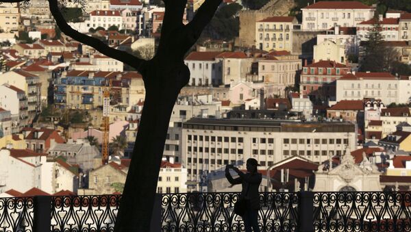 A woman taking pictures from a public garden is silhouetted against the buildings in Lisbon's old town center Wednesday evening, March 15, 2017. - Sputnik International