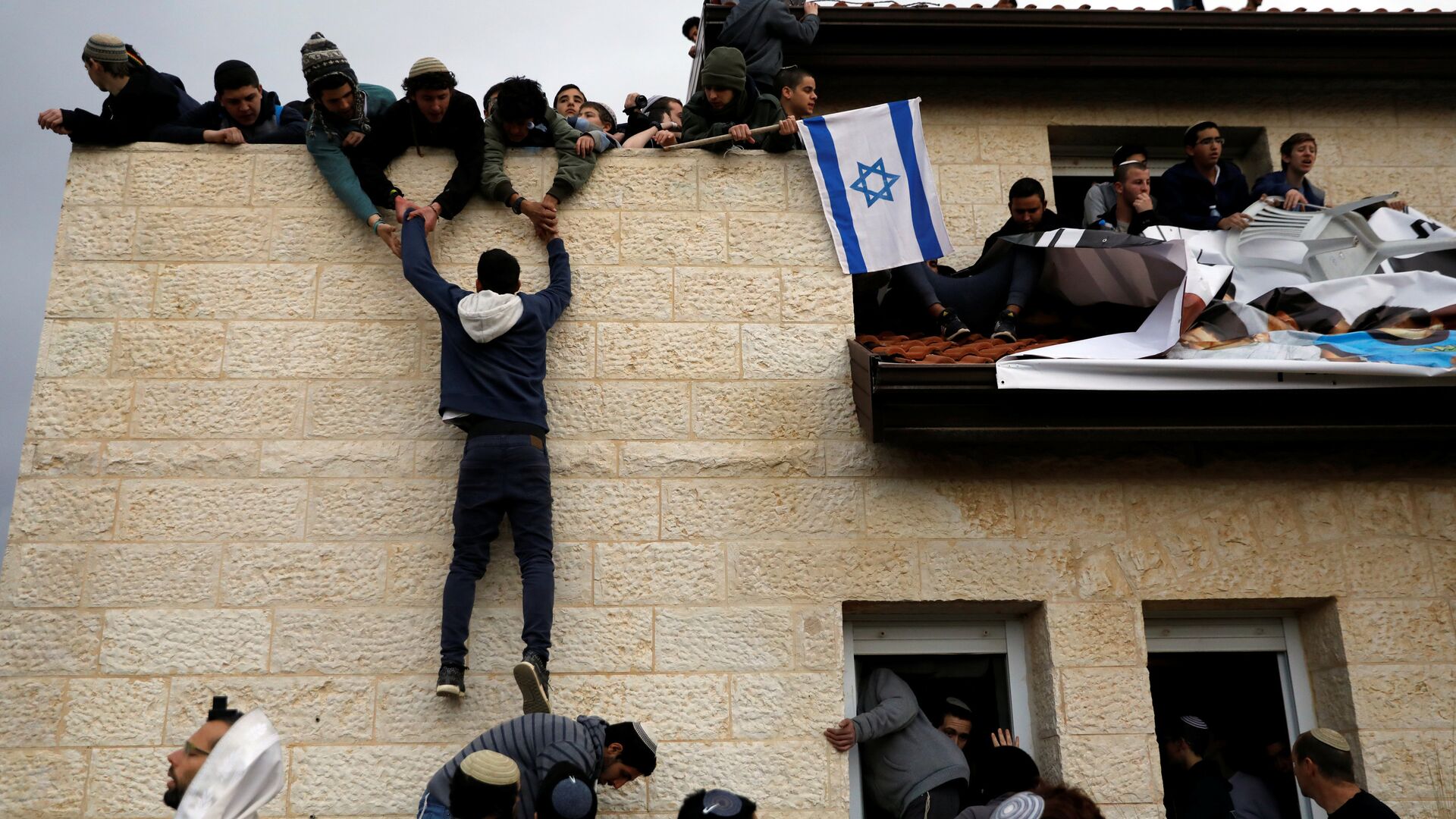 A pro-settlement activist climbs onto a rooftop of a house to resist evacuation of some houses in the settlement of Ofra in the occupied West Bank, during an operation by Israeli forces to evict the houses, February 28, 2017. - Sputnik International, 1920, 09.02.2022