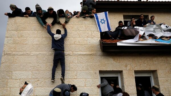 A pro-settlement activist climbs onto a rooftop of a house to resist evacuation of some houses in the settlement of Ofra in the occupied West Bank, during an operation by Israeli forces to evict the houses, February 28, 2017. - Sputnik International