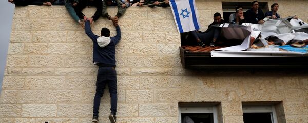 A pro-settlement activist climbs onto a rooftop of a house to resist evacuation of some houses in the settlement of Ofra in the occupied West Bank, during an operation by Israeli forces to evict the houses, February 28, 2017. A pro-settlement activist climbs onto a rooftop of a house to resist evacuation of some houses in the settlement of Ofra in the occupied West Bank, during an operation by Israeli forces to evict the houses, February 28, 2017. - Sputnik International