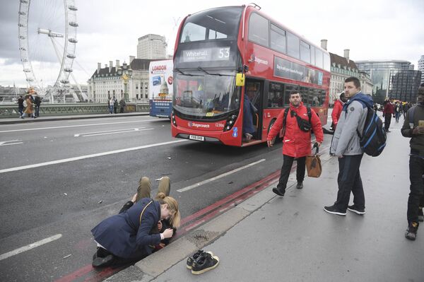A woman assist an injured person after an incident on Westminster Bridge in London - Sputnik International