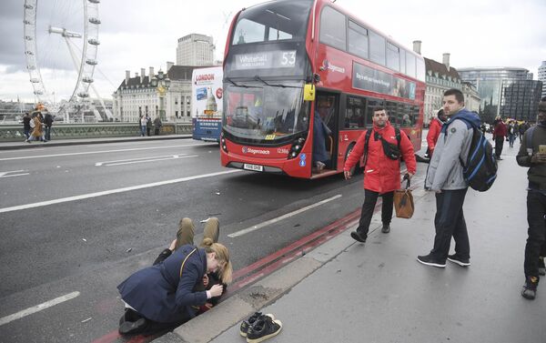 A woman assist an injured person after an incident on Westminster Bridge in London - Sputnik International