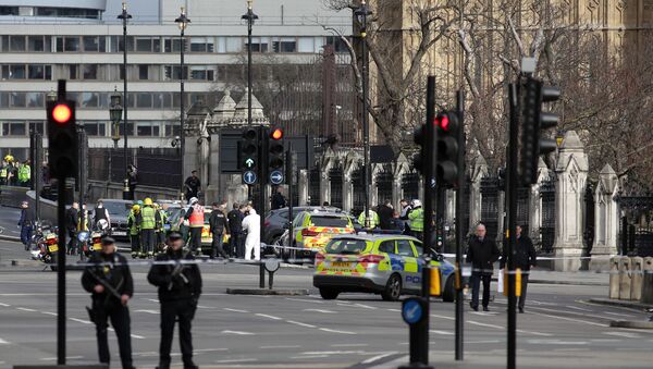Armed police officers stand guard as forensics officers work around a grey vehicle that crashed into the railings of the Houses of Parliament in central London on March 22, 2017, during an emergency inciden - Sputnik International